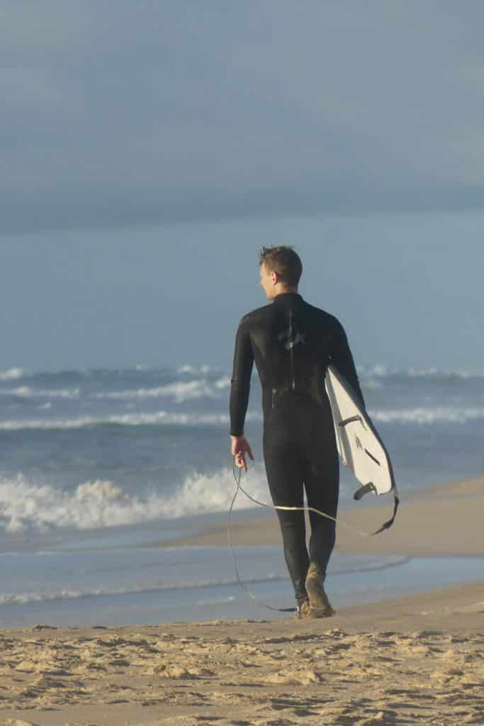 Neoprenanzug im Test: Ein Surfer am Strand mit Backzip Wetsuit