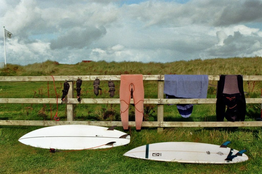 Neprenanzug waschen: Hier hängen Wetsuits über einem Zaun